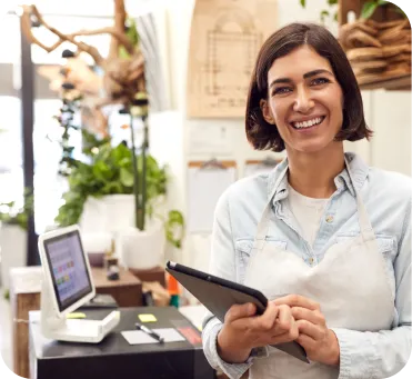 Mujer emprendedora sonriente en su negocio sonteniendo una tableta